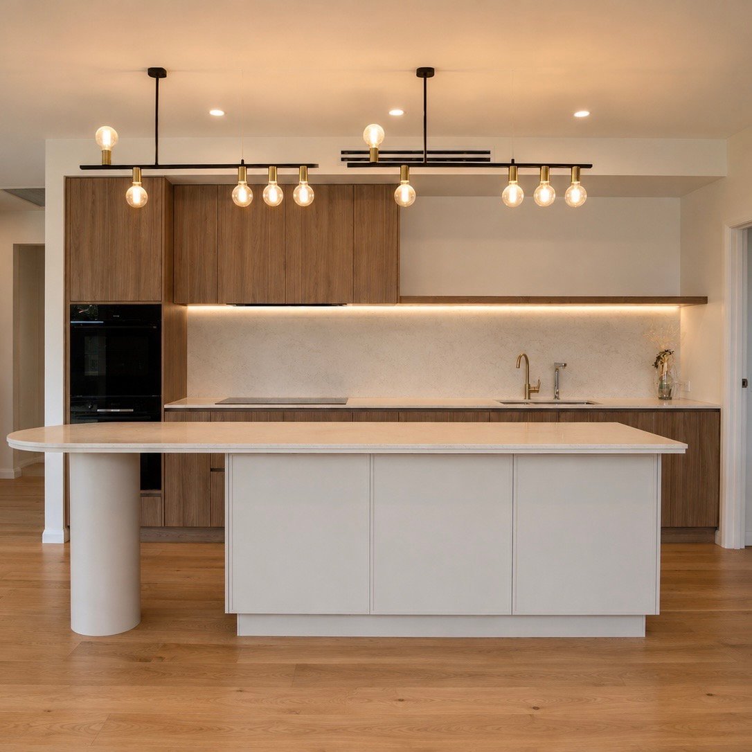 Modern kitchen with white island, wooden cabinetry, pendant lighting, and stainless steel appliances