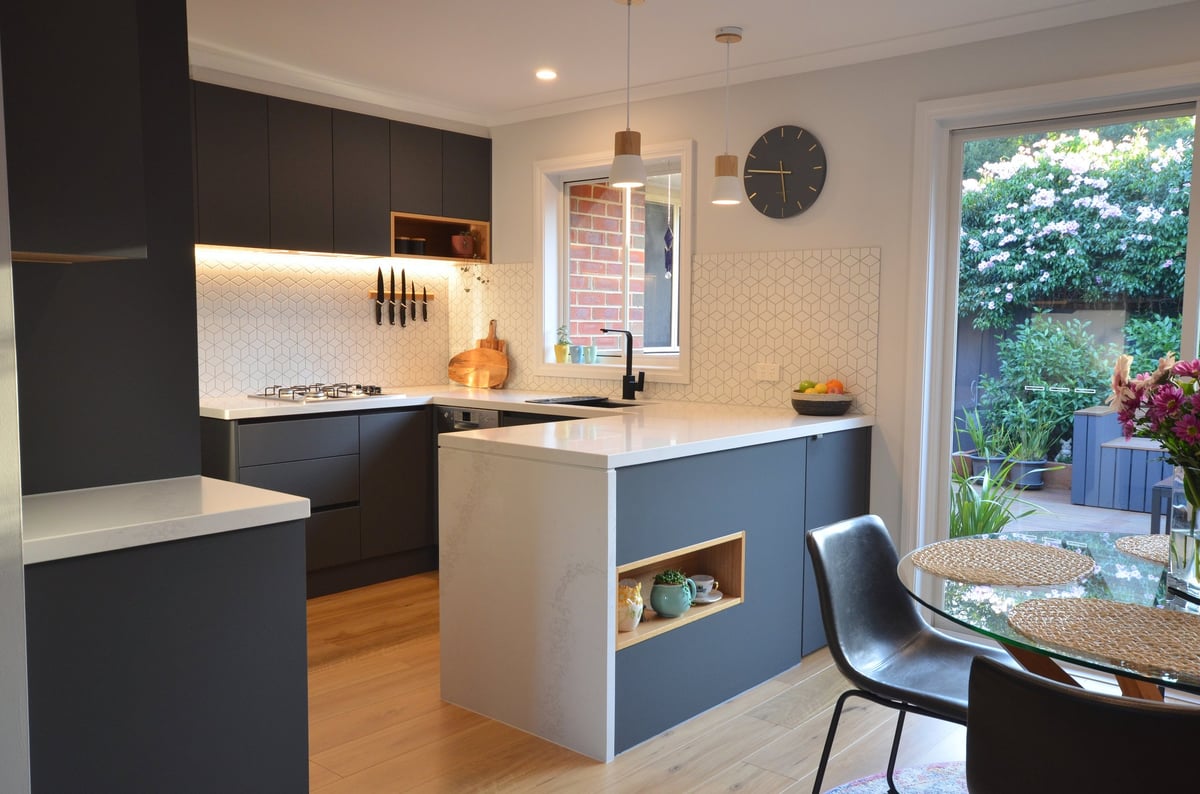 Modern kitchen with dark and white cabinetry, white subway tile backsplash, island with storage, and view to backyard patio.